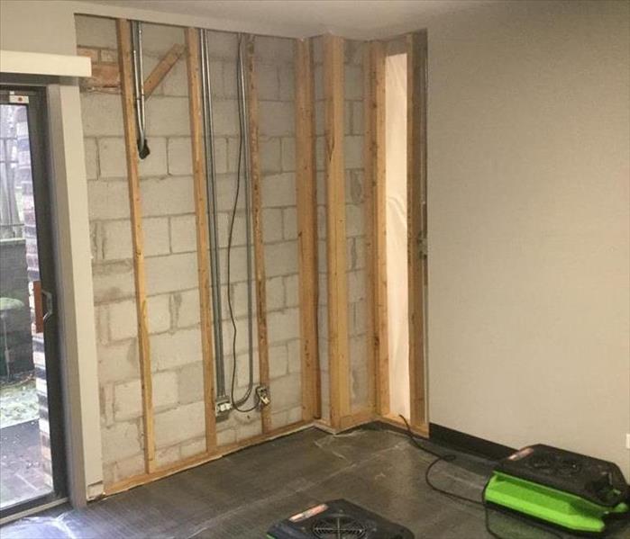 A room with a large portion of drywall removed, leaving the framing studs exposed