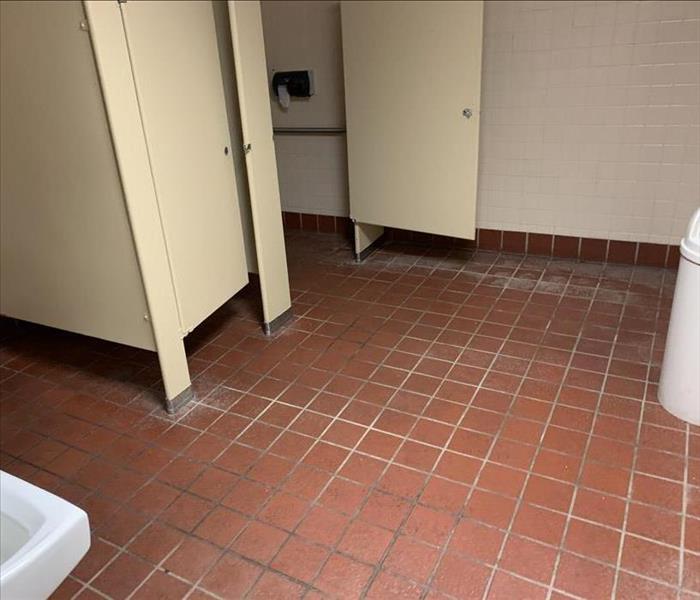 A public bathroom with dirty tile flooring