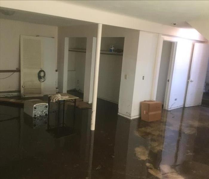 A flooded basement with black standing water and various items left behind