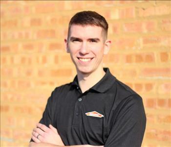 Male SERVPRO employee standing in front of brick wall