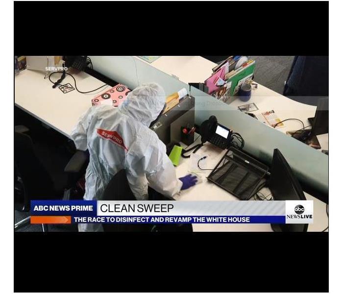 SERVPRO tech wearing a Tyvek suit wiping down an office desk