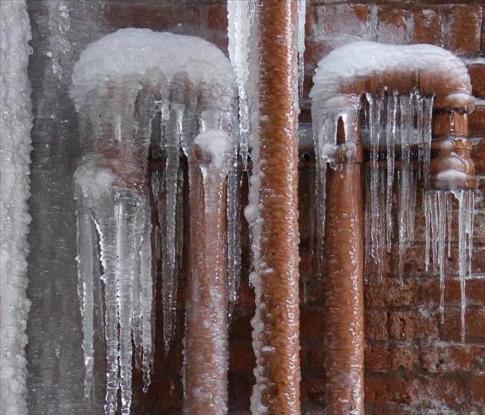 Copper pipes frozen, with ice and large icicles forming around them