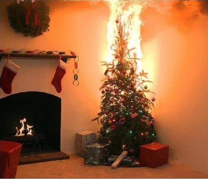 A living room with stockings hung up over a fire place and a decorated Christmas tree set on fire