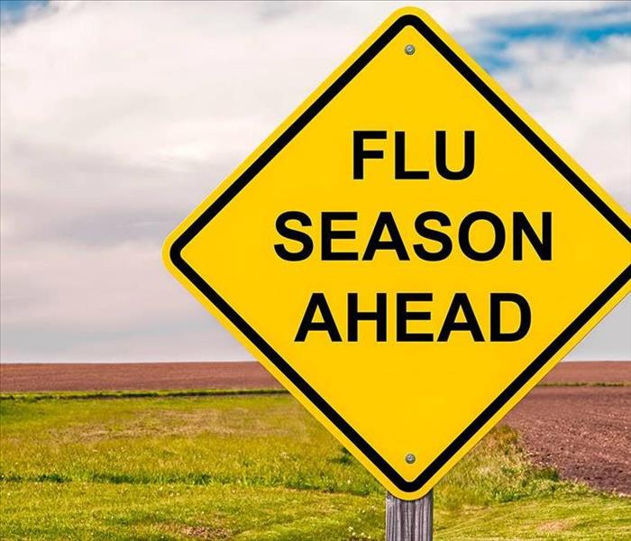 A yellow sign in the middle of a field that say "Flu Season Ahead"