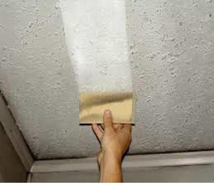 A chem sponge is used to wipe soot and smoke residue off a drywall ceiling