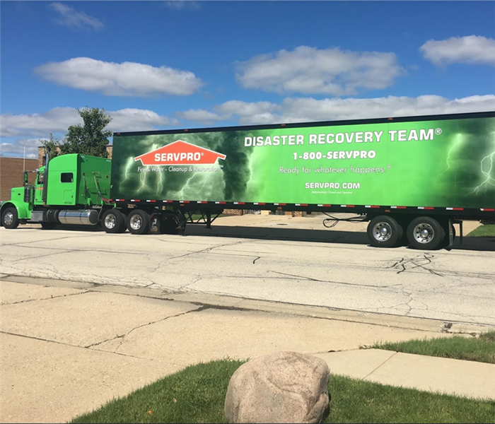 Large green SERVPRO semi-truck parked in the street in daylight